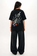 Person wearing a black t-shirt with colorful graphics on the back, standing against a white background
