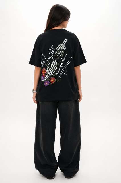 Person wearing a black t-shirt with colorful graphics on the back, standing against a white background