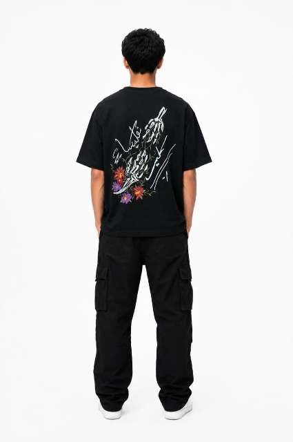 Person wearing a black t-shirt with a graphic design on the back, standing against a white background