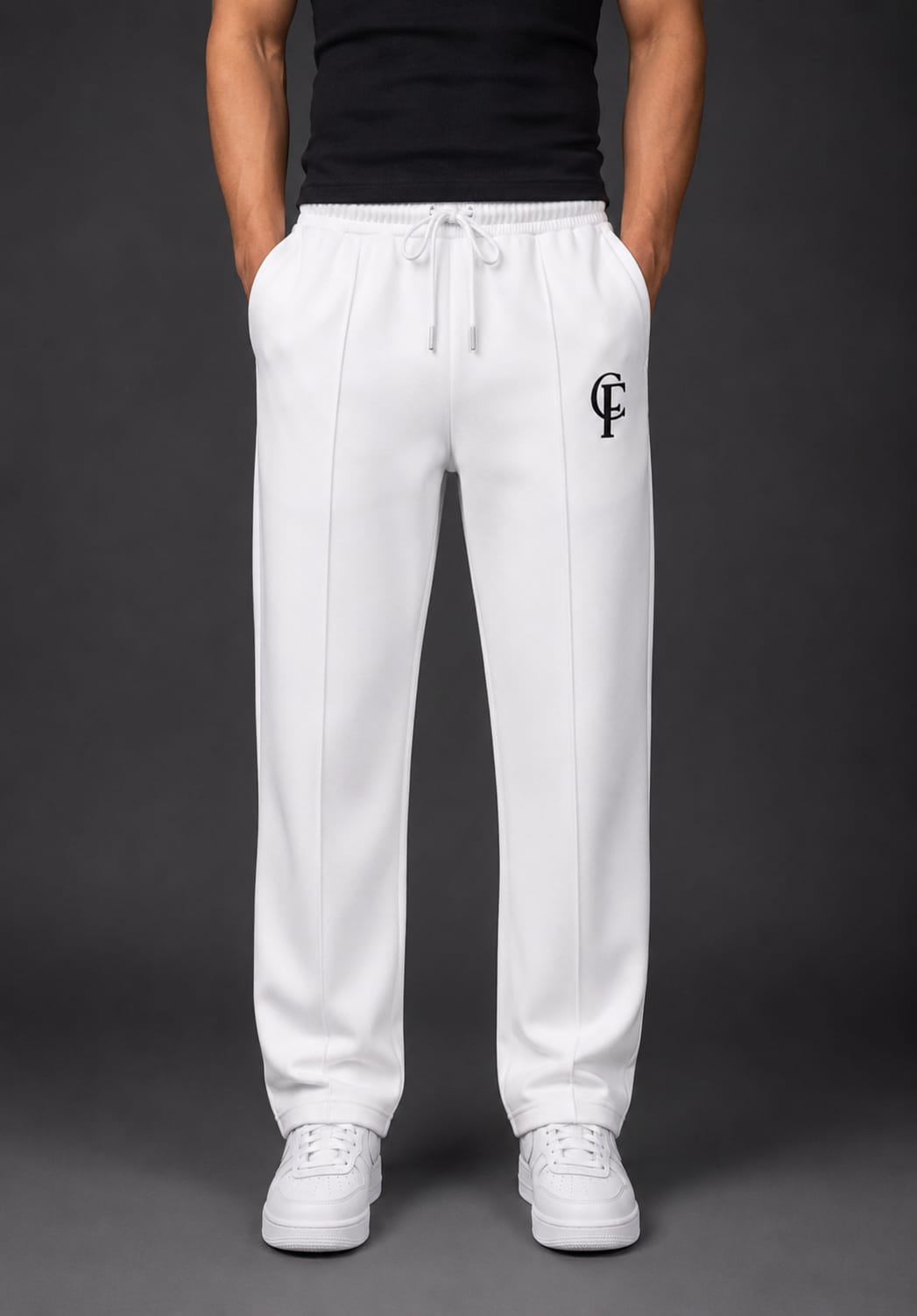 White Trouser with a black DTF FlexaClub "FC" logo on the left thigh, worn by a model with a black shirt and white sneakers against a dark gray background.