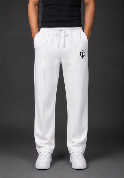 White Trouser with a black DTF FlexaClub "FC" logo on the left thigh, worn by a model with a black shirt and white sneakers against a dark gray background.