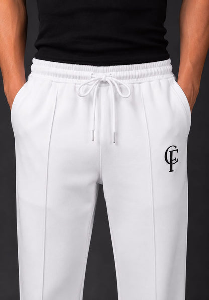 White Trouser with a blackDTF FlexaClub "FC" monogram logo on the left thigh, modeled with a white tank top and white sneakers against a dark gray studio background.