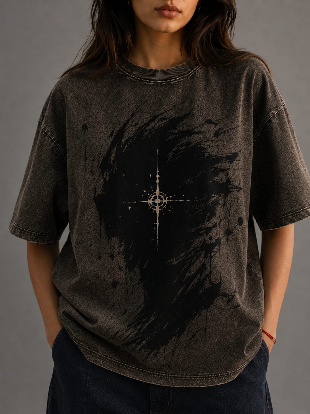 Person wearing a dark t-shirt with a central design on a gray background
